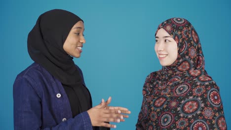 Asian-Muslim-woman-and-African-Muslim-woman-chatting,-smiling.-Muslim-brotherhood.